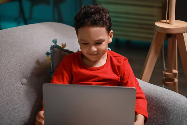 Piccolo ragazzo afroamericano che guarda cartoni animati sul computer portatile a casa a tarda sera - Foto, immagini
