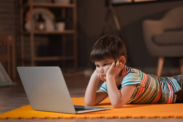 Kleine jongen kijken cartoons op laptop thuis laat in de avond - Foto, afbeelding