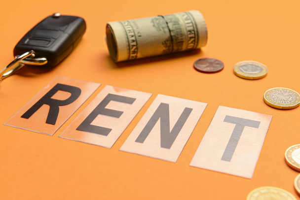 Word RENT με κλειδί αυτοκινήτου και τα χρήματα σε πορτοκαλί φόντο, closeup - Φωτογραφία, εικόνα