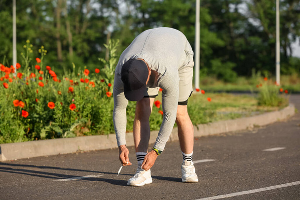 Αθλητικός ώριμος άνδρας που δένει κορδόνια στο δρόμο - Φωτογραφία, εικόνα