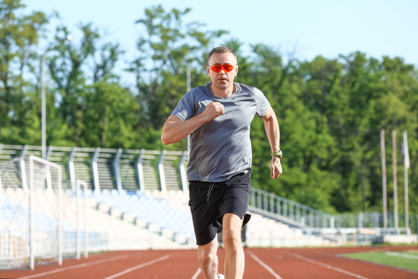 Sportieve volwassen man joggen in het stadion - Foto, afbeelding