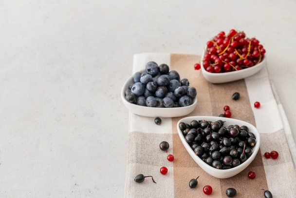Bowls with different ripe berries on light background - Valokuva, kuva