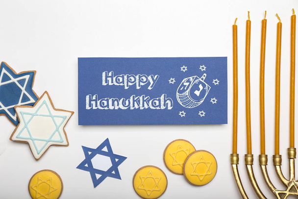 Biscoitos saborosos e cartão de saudação para Hanukkah e menorah no fundo branco - Foto, Imagem