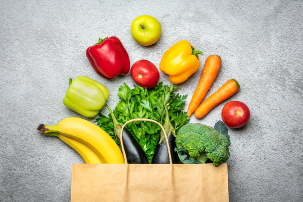 Eco friendly paper shop bag with raw organic green vegetables isolated on green background Flat lay, top view Zero waste, plastic free concept - 写真・画像