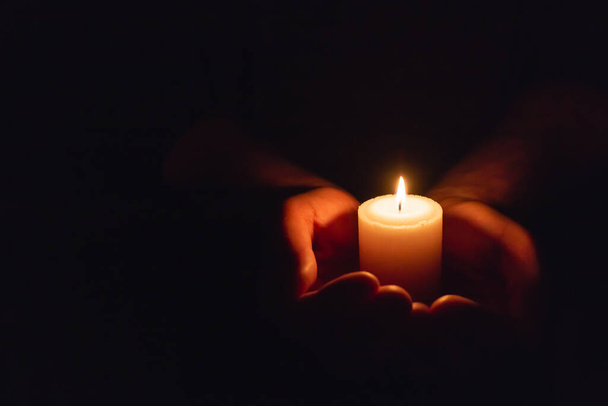 Hands holding burning candle in dark like a heart.Selective focus,black background.Copy space. - Foto, immagini