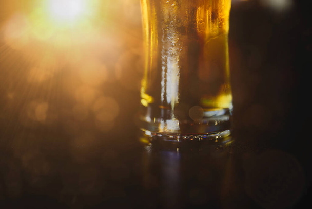 Glass of beer on a table in a bar on blurred bokeh background - Fotografie, Obrázek