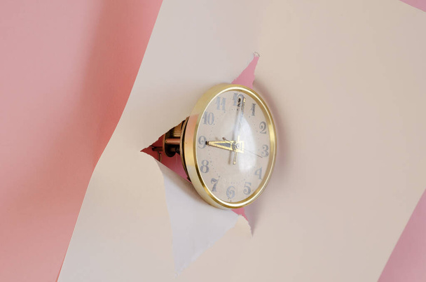 Vintage clock, white tear paper, pink background. Round Mechanical table clock in gilded frame. Selective focus. - Photo, Image