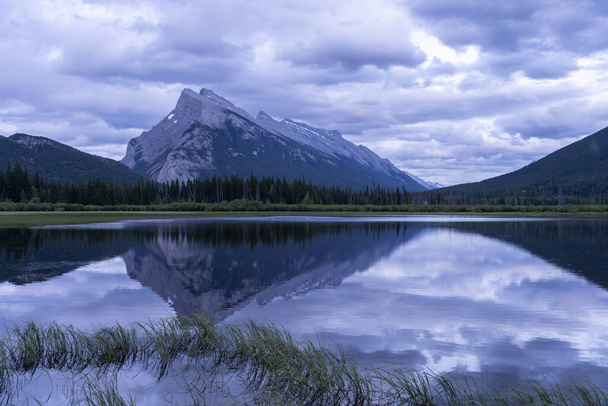 Moody sunset in Canadian Rockies with mountain reflecting on a lake s, surface, Banff National Park, Canada - Foto, imagen