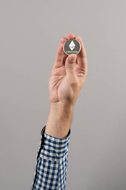 Ethereum cryptocurrency price up. Close up of man holding silver coin of Ethereum. Digital Money - Fotó, kép