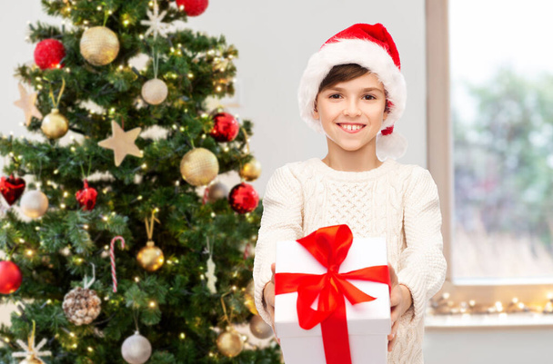 smiling happy boy in santa hat with christmas gift - Photo, Image