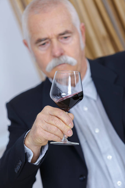 elderly man holding a glass of wine - Фото, зображення