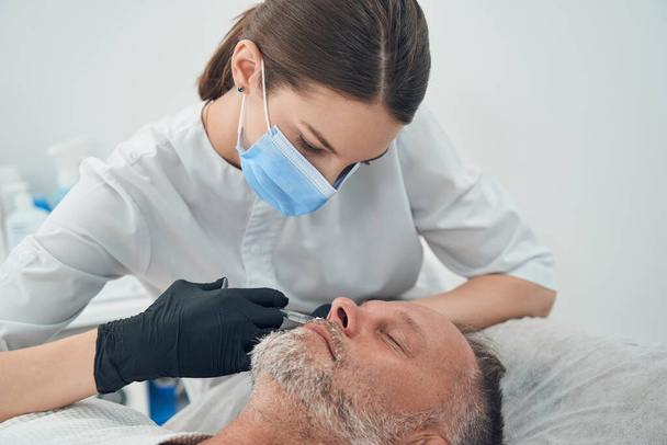 Homme recevant une injection anti-âge dans une clinique de cosmétologie - Photo, image