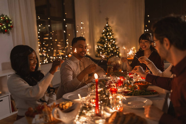 happy friends with sparklers at christmas dinner - Foto, imagen