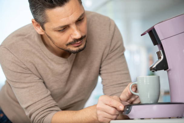 handsome man making coffee with a coffee machine - Foto, afbeelding