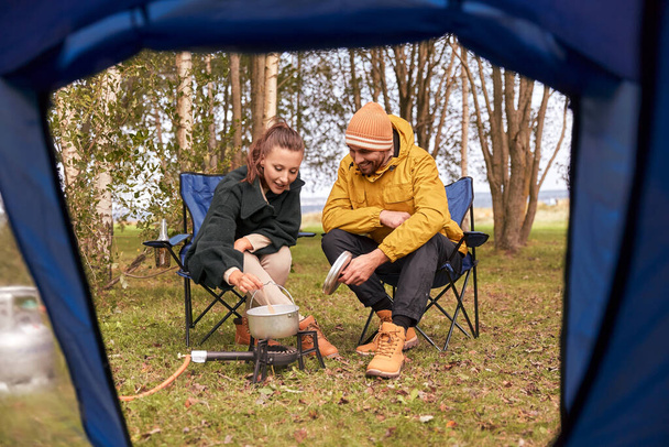 couple cooking food on gas burner at tent camp - Foto, Imagen