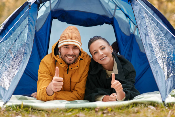 happy couple lying inside tent at campsite - Фото, изображение