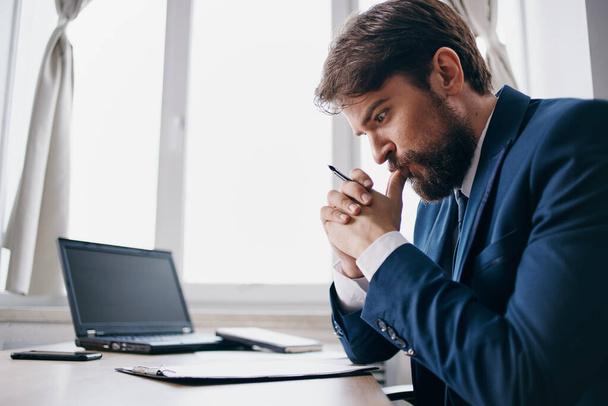bearded man sitting at a desk in front of a laptop - Fotoğraf, Görsel