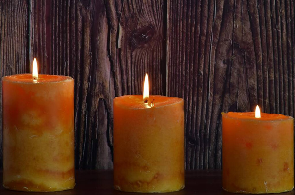 tres velas de cera naranja sobre fondo de madera - Foto, Imagen