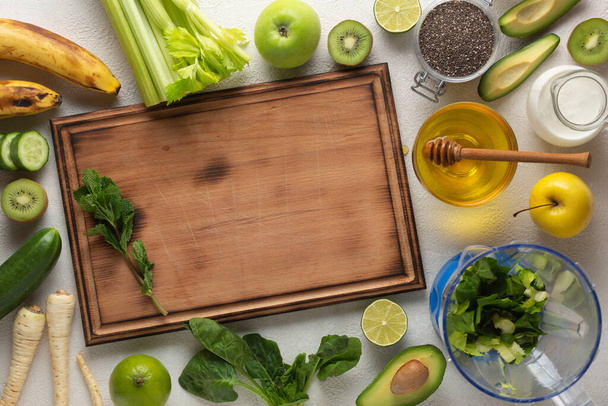 Πράσινα λαχανικά και φρούτα για ένα πράσινο ποτό αποτοξίνωσης σε ένα ελαφρύ τραπέζι, top view - Φωτογραφία, εικόνα