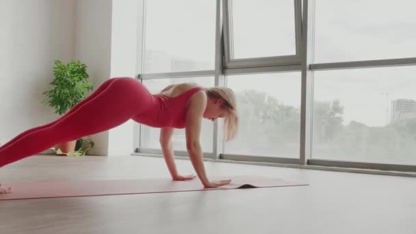 Hermoso yoga. Mujer joven en uniforme deportivo rojo hace suave onda corporal. concepto de estilo de vida saludable - Metraje, vídeo