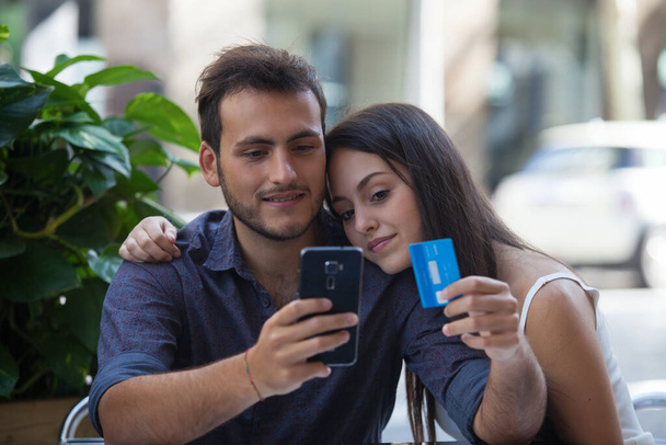 Szczęśliwa para płaci online z karty kredytowej i smartfona na ulicy - Zdjęcie, obraz