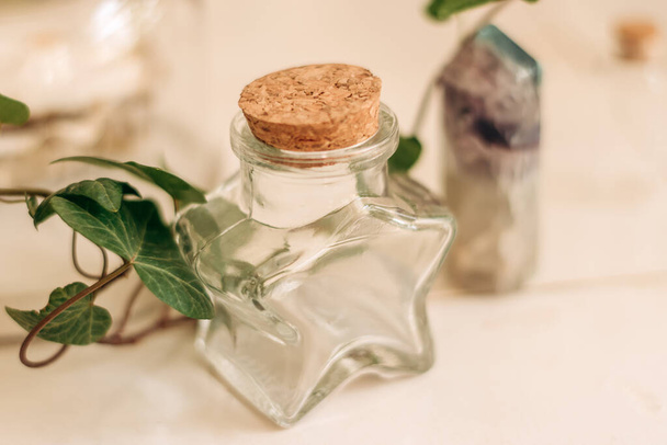 A glass bottle in the shape of a star, a houseplant and a mineral on a white table.Elements of the home interior.Creative background.Selective focus. - Photo, image