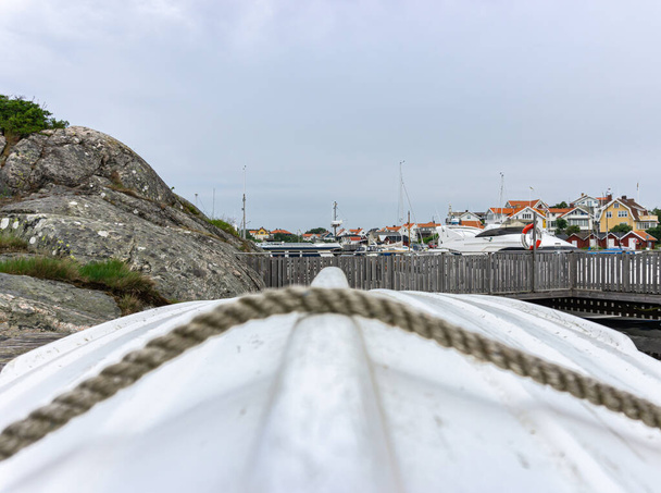 Ockero, Suecia - 10 de junio de 2021: Cuerdas borrosas en primer plano y un pequeño pueblo detrás del barco - Foto, imagen