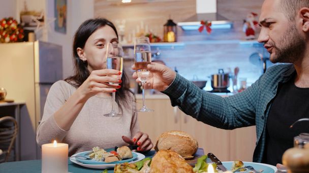 Мужчина и женщина едят курицу и звонят в бокалы с шампанским - Фото, изображение
