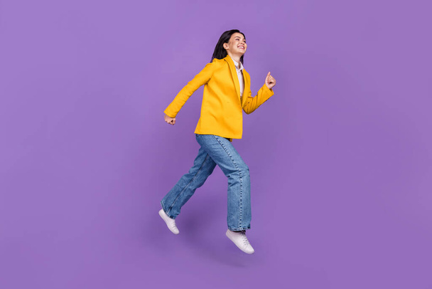 Full size photo of excited cool happy businesswoman jump go empty space smile isolated on purple color background. - Фото, изображение