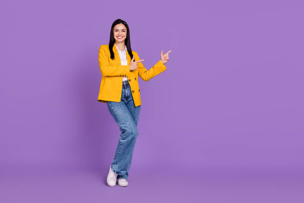 Photo of sweet shiny young woman dressed yellow blazer pointing fingers empty space smiling isolated purple color background. - Фото, изображение