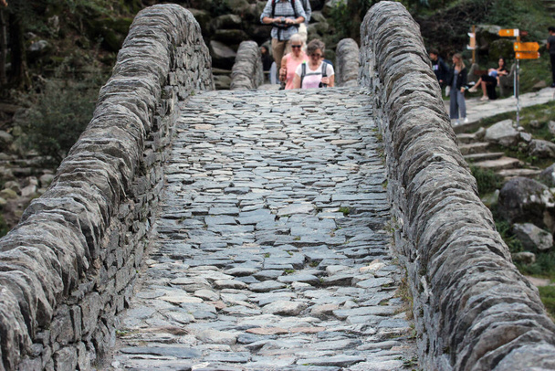 Verzasca Vadisi 'ndeki muhteşem çift kemerli taş köprü Ponte dei salti üzerinde odakları kesilmiş insanlar. - Fotoğraf, Görsel