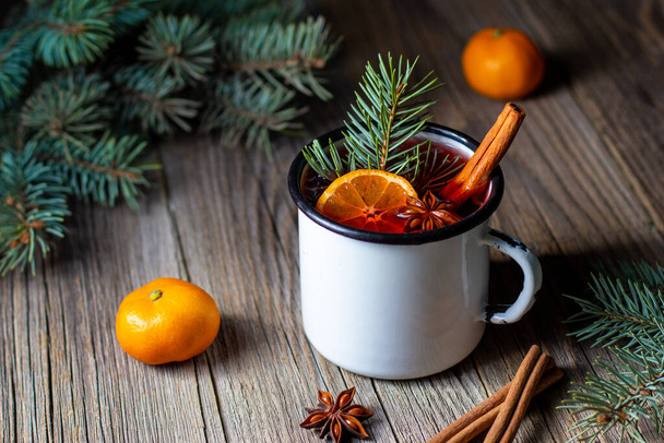 Traditional tasty mulled wine with mandarin apple spices and christmas tree in white cup. Autumn hot drink - Photo, Image