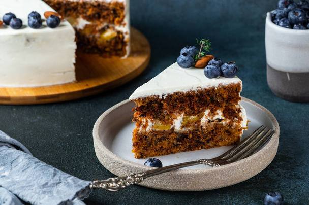 piece of carrot cake with walnuts and blueberry on dark background. Local food. Traditional american cake. Cake for thanksgiving day. Christmas cake - Fotoğraf, Görsel