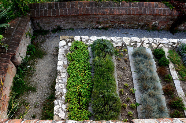 herb beds in rows above a limestone stone back, a brick walled courtyard with a gravel path in the park. monastic healing garden with a focus on the blind. the blind try scents and textures.  - Photo, Image