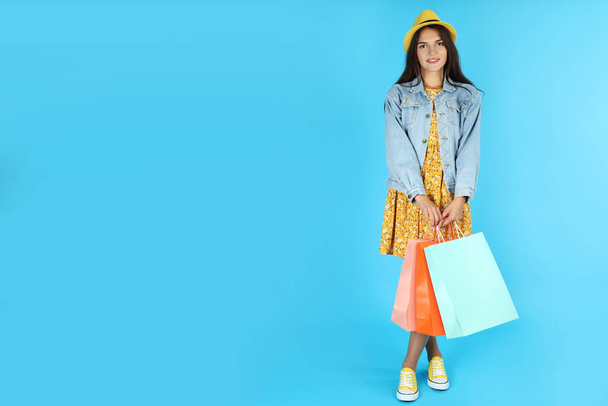 Attractive girl with multicolored paper bags on blue background. - Fotografie, Obrázek