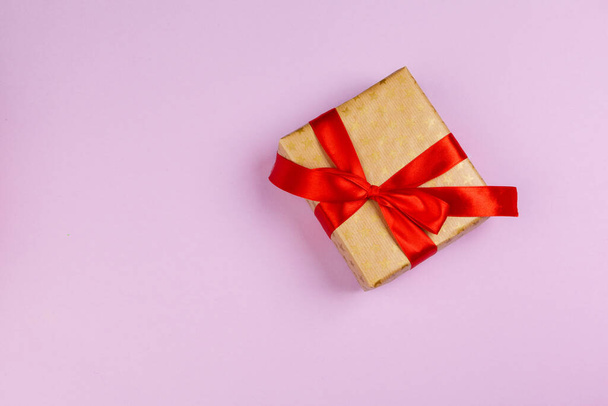 Top view of a decorated present with a bow on pink background - Fotó, kép