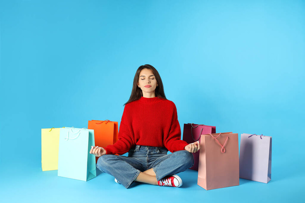 Girl with multicolored paper bags on blue background. - Fotografie, Obrázek