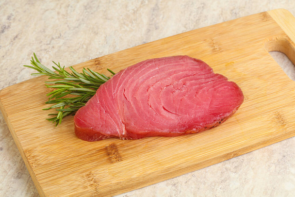 Raw tuna steak for cooking over board served rosemary - Fotó, kép