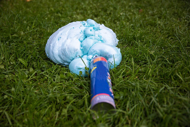 An exploded cylinder with construction foam on the grass. Balloon defect, close-up, home repairs - Фото, изображение
