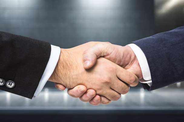 Handshake of two businessmen on the background of night exterior of the business center, partnership concept, close up - Zdjęcie, obraz