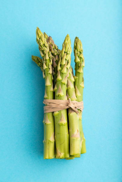Bunch of fresh green asparagus on blue pastel background. Top view, flat lay, close up. harvest, healthy, vegan food, concept, minimalism. - Fotó, kép