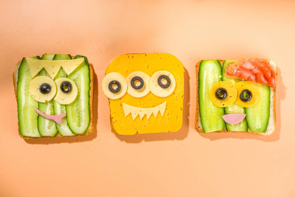 Verschiedene lustige Monster-Halloween-Sandwiches. Set-Sortiment kreativer Frühstückssnack Toasts mit Käse, Halloween-Kinderparty-Essen, Draufsicht  - Foto, Bild
