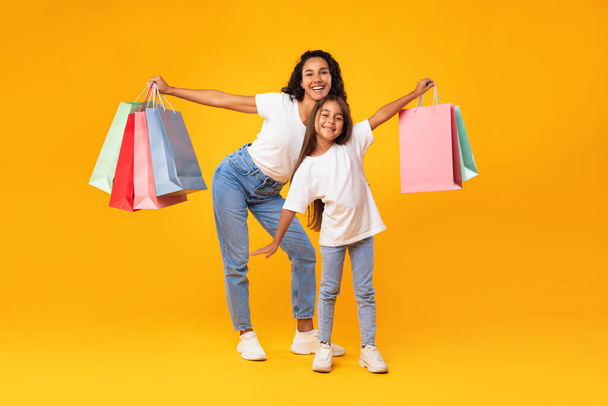 Arabo madre e figlia shopping holding shopper borse, giallo sfondo - Foto, immagini