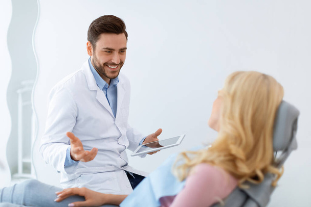 Homem dentista alegre ter conversa com paciente mulher loira - Foto, Imagem