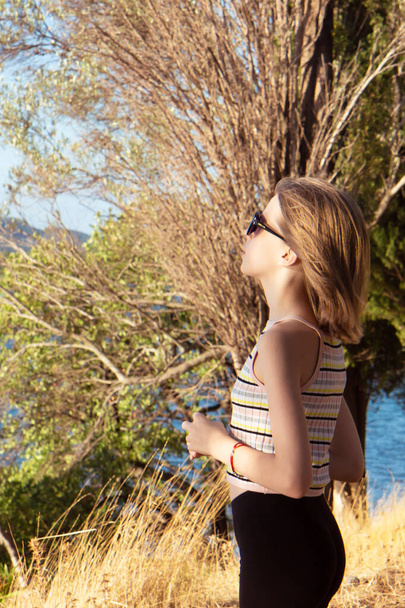 Mladý krásný dospívající dívka stojí na pobřeží a má krajinu - Fotografie, Obrázek