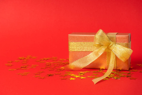 Geschenkschachtel in Goldfolie mit goldener Schleife auf sternenfarbenem Hintergrund. Mit Platz für Text - Foto, Bild