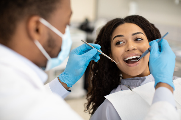 Junge Afroamerikanerin bei Zahnarzt in moderner Klinik untersucht - Foto, Bild