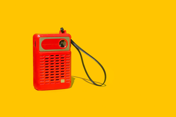 Una radio portátil roja vintage sobre un fondo amarillo - Foto, imagen