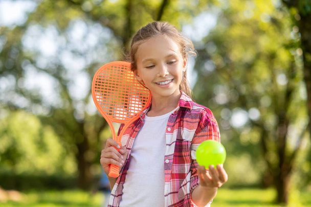 Smiling girl with tennis racket and ball - Фото, изображение