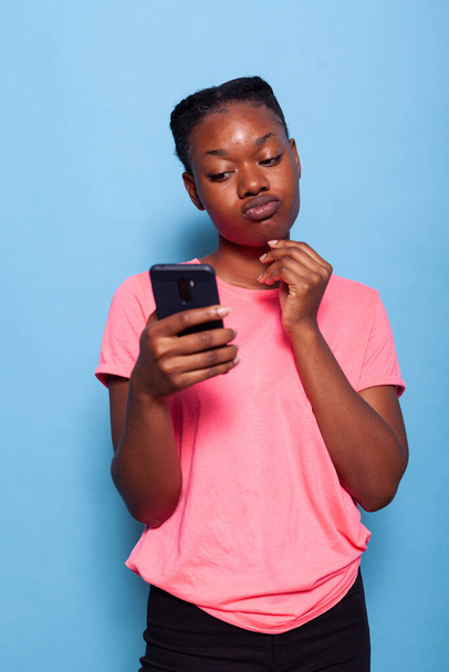 Portrait of african american young woman chatting with friend using smartphone - Foto, afbeelding